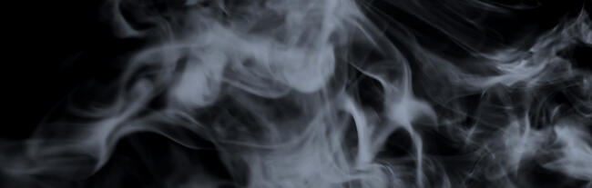white whispy smoke floats in front of a black background